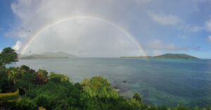 Semi-circle rainbow over blue water against a blue sky