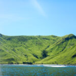 Hilly green island against a pale blue sky