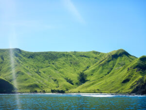 Hilly green island against a pale blue sky