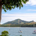 4 sailboats on the water with hills in the background