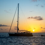 Yacht at anchor against a sunset backdrop