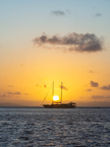 Setting sun between two masts of a double-masted yacht