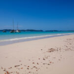 Beach foreground with sailboats on the horizon