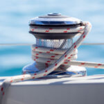 Close up of a yacht winch wrapped in red and white line