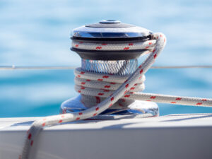 Close up of a yacht winch wrapped in red and white line